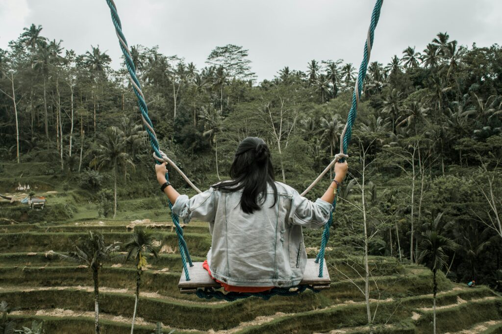 pexels-photo-10835265-10835265 A woman in a denim jacket enjoys a swing with a scenic view of the lush rice terraces in Ubud, Bali.